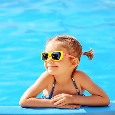 Un bambino sorride a bordo piscina. La durezza dell'acqua nelle piscine può danneggiarne le superfici e corrodere i tubi.